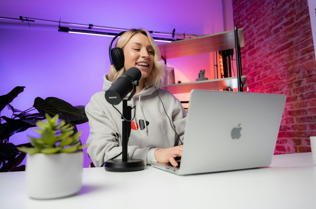 Young woman smiling while writing code on a laptop at a desk