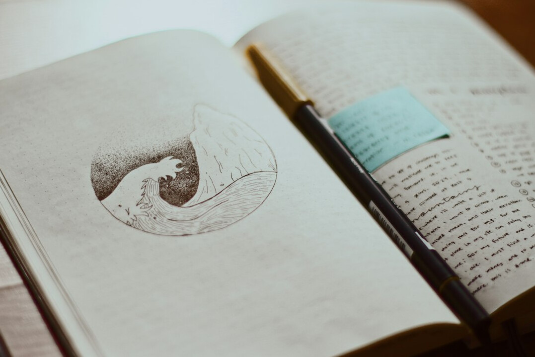Open notebook with handwritten diagrams and a pen