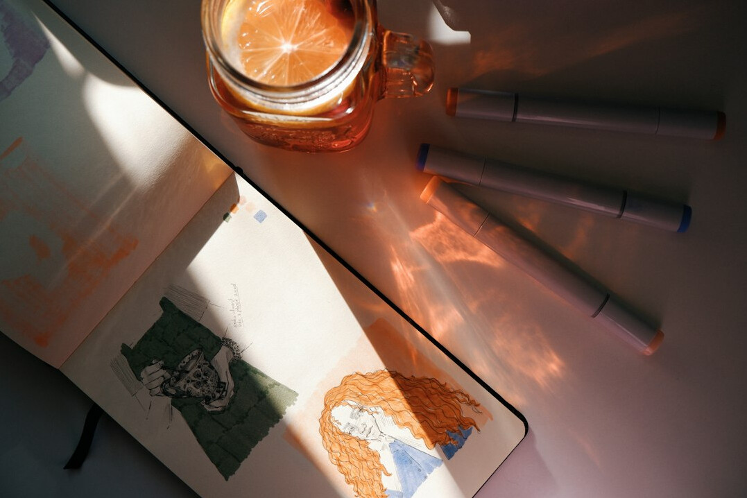 Overhead view of a desk with a notebook, pen and cup of tea