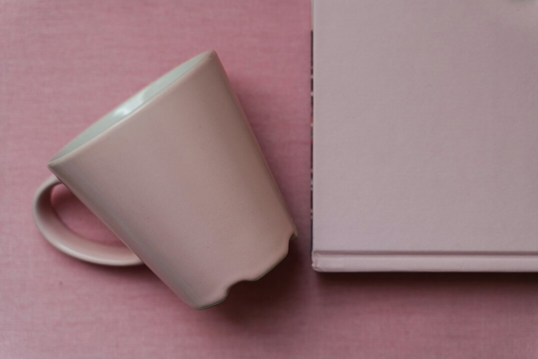 Flat lay of a desk with open notebook, laptop and coffee cup